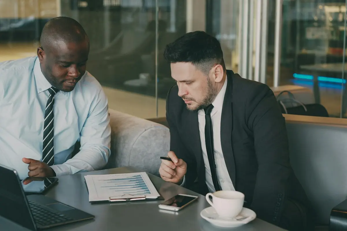 Two businesspeople discussing documents at a cafe table