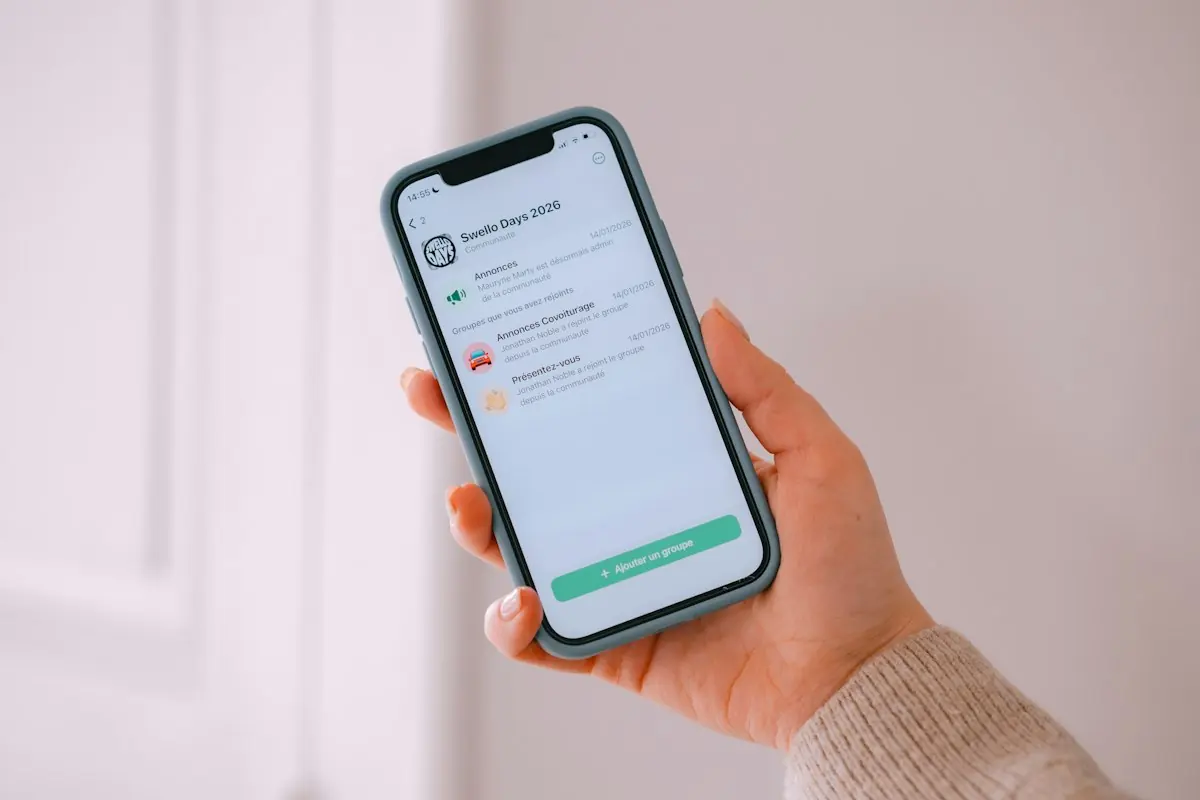 Hand holding an iPhone displaying a WhatsApp broadcast channel