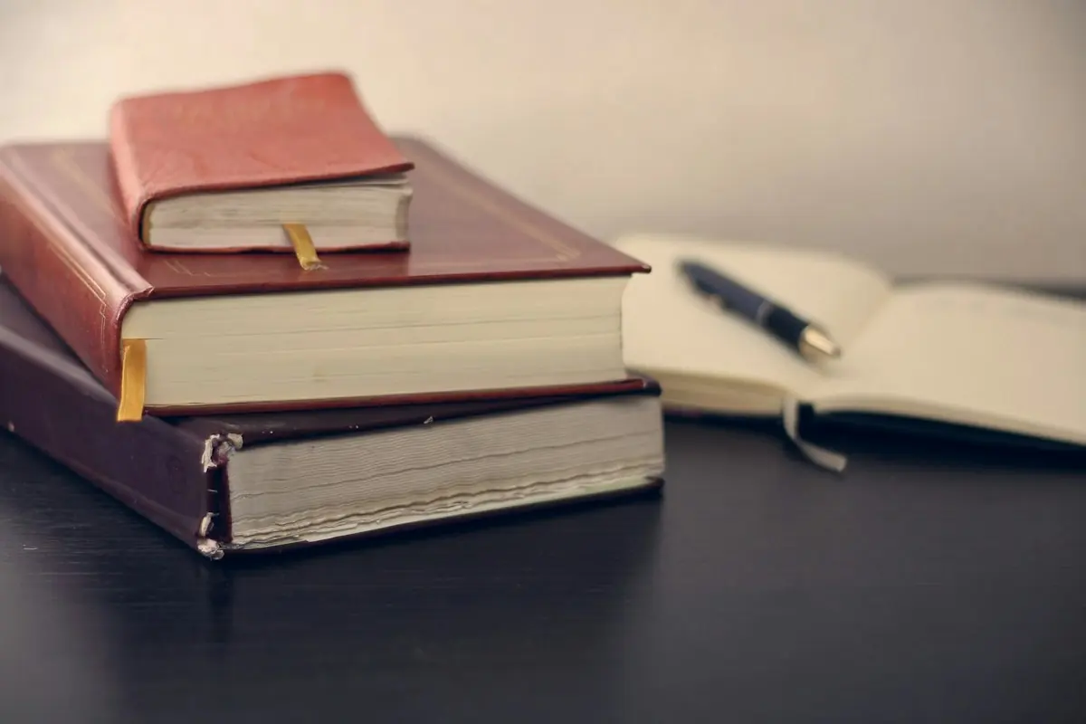 Stacked books and an open writing journal on a desk